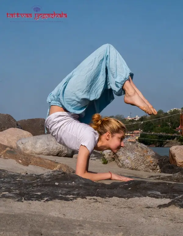 A student in mayurasana on the rocks beside the Ganges, Rishikesh