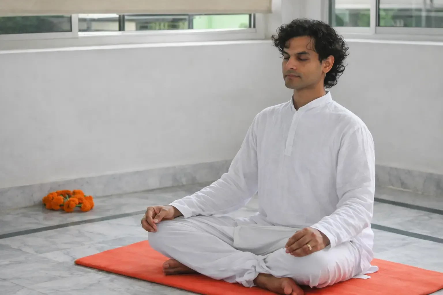 A practitioner seated in meditation on a terrace at Tattvaa Yogashala