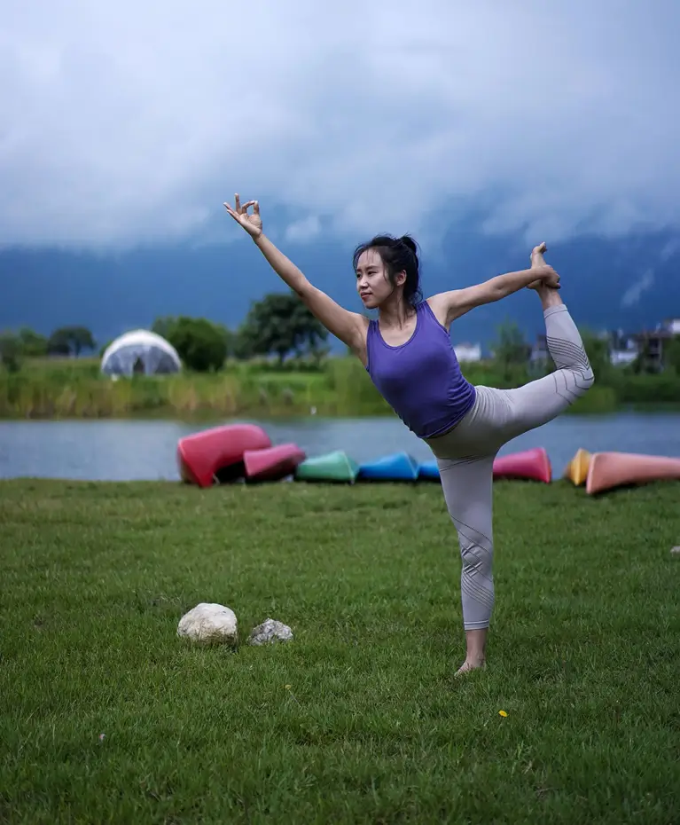 A student in a standing balance beside the water during a retreat