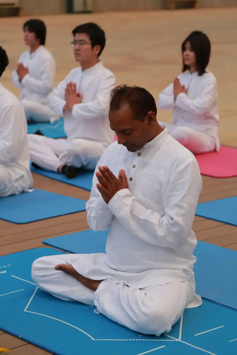 A group seated in meditation, hands at the heart