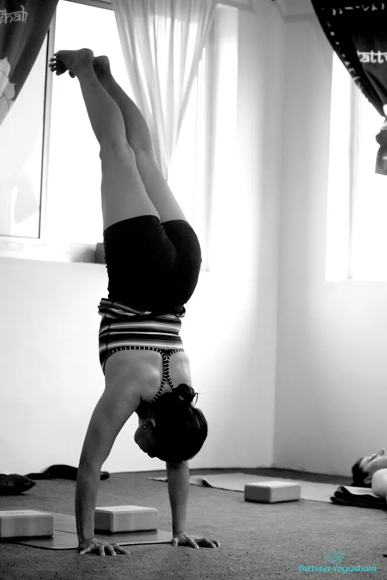 A student holding a handstand by the window during the 300 hour Ashtanga yoga teacher training at Tattvaa Yogashala, Rishikesh